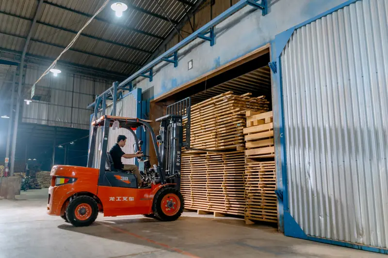 Carretilla elevadora cargando palets de madera en un almacén